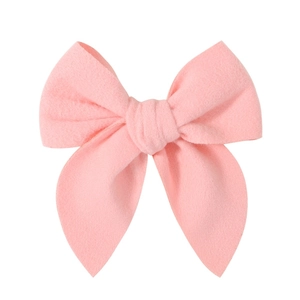 Close-up of light pink plush bow hair clip with soft textured fabric and elegant center knot
