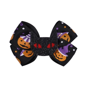 Detail of Halloween bow hair clip featuring pumpkin prints and a sparkly black cat motif