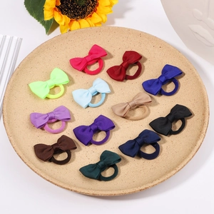 Set of 12 colorful grosgrain ribbon bow hair ties for girls on a white ceramic plate