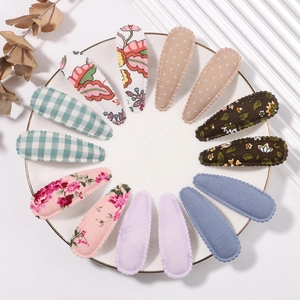 12-piece floral fabric snap hair clips set with lace edges in a white ceramic dish