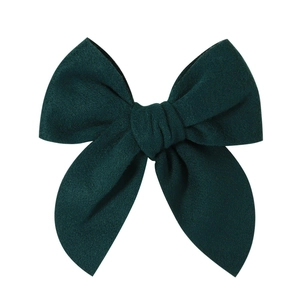 Detailed close-up of dark green velvet bow hair clip with rich texture and soft finish