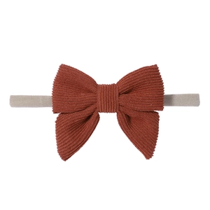 Dettaglio della fascia per neonati con fiocco in velluto a coste color arancio bruciato
