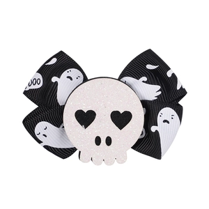 Detail view of Halloween bow hair clip with white ghost patterns and a glittery skull center