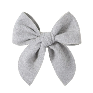 Close-up of light grey knitted bow hair clip with fine fabric texture on white background