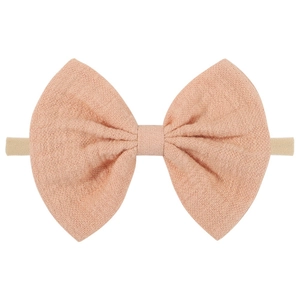 Detail of soft peach cotton linen baby bow headband with textured weave and elastic nylon band