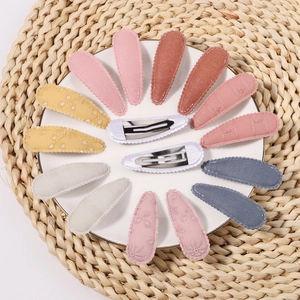 Floral embroidered fabric BB hair clips for girls set on a decorative white porcelain plate