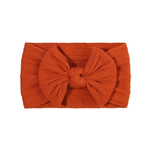 Close-up of cable-knit texture and large bow on rust orange elastic baby headband