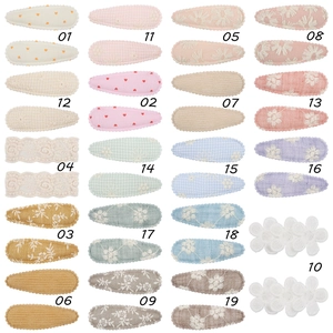 Detail view of 19 assorted fabric hair clips with lace, embroidery and floral patterns