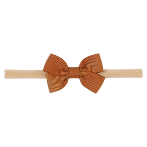 Détail d'un nœud papillon marron sur un bandeau en nylon beige sans couture pour bébé