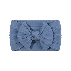 Détail d'un bandeau pour bébé en maille torsadée bleu poudré avec un grand nœud fait main
