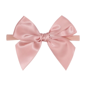 Soft pink nylon baby headband with a shiny satin bow tie, minimalist aesthetic