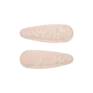 Detail of pink fabric hair clips featuring white embroidered daisy patterns and lace edges
