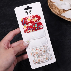 Detail of six floral embroidery snap hair clips with wavy edges on black background