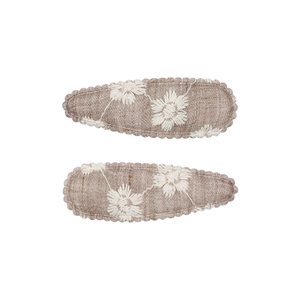 Close-up of two vintage embroidered fabric hair clips with white daisy patterns