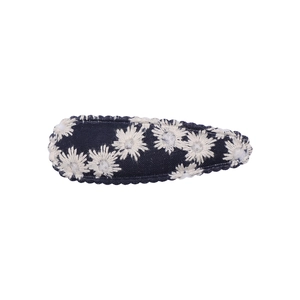 Detailed embroidery of white daisies on a navy blue denim hair clip with wavy stitching
