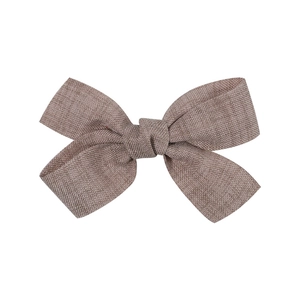 Detail of soft linen fabric texture on a brown baby bow hair clip with classic knot