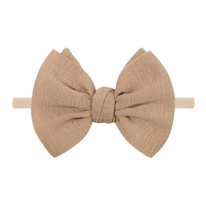 Detailed view of earth-toned fabric bow headband with elastic strap for infants and toddlers