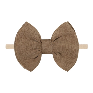 Détail d'un nœud en tissu marron texturé fixé sur un bandeau bébé en nylon rose élastique
