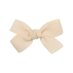 Detailed macro view of the handmade cream fabric bow clip with plain weave texture