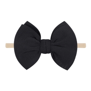 Détail d'un bandeau à nœud noir en tissu doux avec élastique nude pour bébés
