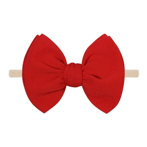 Gros plan d'un grand nœud rouge texturé sur un bandeau élastique souple pour bébé
