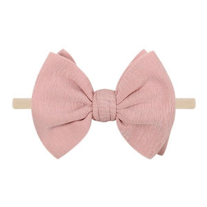 Texture détaillée d'un bandeau bébé en lin vieux rose avec un grand nœud souple