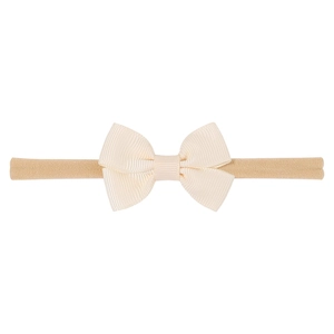 Close-up of handmade cream grosgrain ribbon bow with soft elastic nylon baby headband
