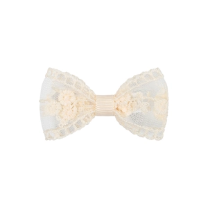 Détail d'une barrette nœud en dentelle ivoire avec des motifs floraux brodés
