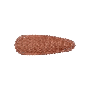 Détail d'une pince à cheveux en tissu caramel avec bords festonnés pour filles