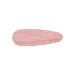Détail d'une pince à cheveux rose en tissu avec tissage texturé et bordure festonnée brodée