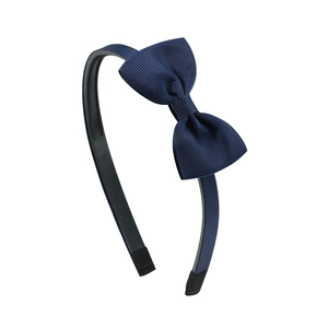 Detail of navy blue bow headband showing grooved anti-slip inner surface and ribbon texture
