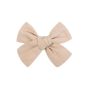 Détail d'une pince à cheveux nœud en lin beige faite main montrant la texture du tissu