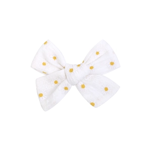 Detailed macro view of white cotton bow hair clip with yellow daisy embroidery patterns