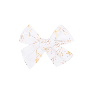 Detail of handmade cotton hair clip showing white fabric texture and yellow leaf pattern