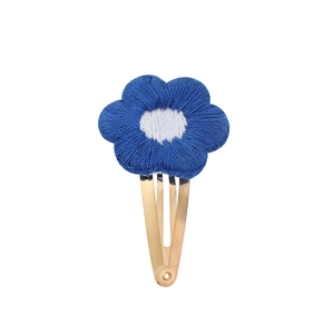 Détail de la pince à cheveux fleur brodée bleue et blanche avec finition métal doré