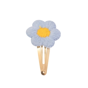 Détail d'une barrette à fleurs au crochet faite main avec pétales bleus et cœur jaune