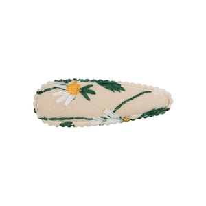 Detailed close-up of a floral embroidered BB hair clip with white lace trim and daisy pattern