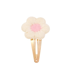 Close-up of handmade crochet flower hair clip featuring cream petals and a pink center