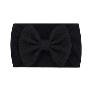 Détail du bandeau bébé en nylon noir avec un grand nœud décoratif à texture côtelée