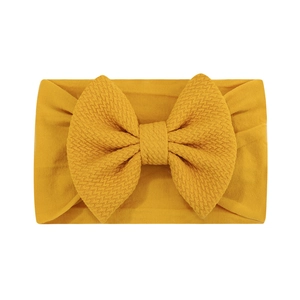 Détail du bandeau bébé jaune moutarde avec nœud à texture gaufre sur fond blanc