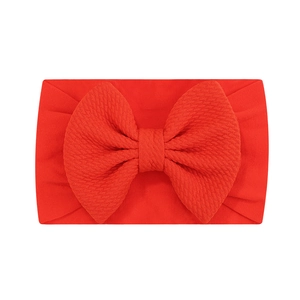 Gros plan détaillé d'un bandeau bébé en nylon jacquard rouge avec un grand nœud doux
