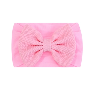 Gros plan du bandeau rose pour bébé avec texture gaufrée et grand nœud décoratif