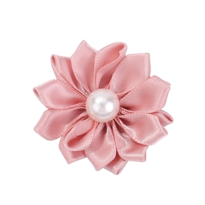 Vue détaillée d'une fleur en satin rose faite main avec une perle blanche au centre du bijou