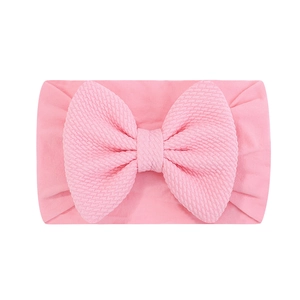 Détail du bandeau pour bébé avec tissu à texture nid d'abeille et grand nœud rose