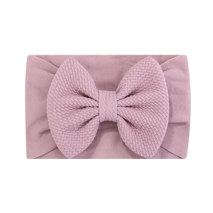 Détail du bandeau bébé rose poudré montrant le nœud gaufré et le tissu extensible