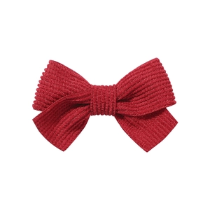 Close-up of a red corduroy bow hair clip with detailed ribbed texture on a white background