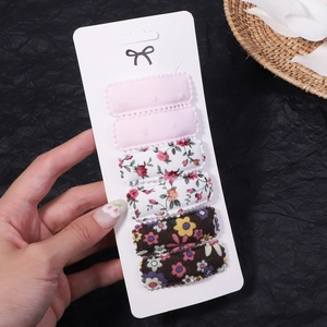 Set of six floral and solid fabric BB clips on display card held by hand