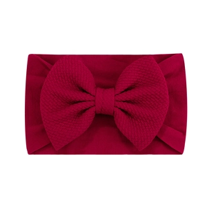 Détail du bandeau bébé jacquard rouge vin avec un grand nœud en texture gaufre