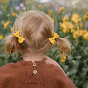 Toddler yellow grosgrain ribbon hair clips with daisy print in double ponytail hairstyle