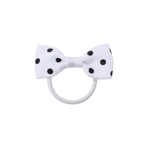 Dettaglio di un elastico per capelli con fiocco bianco a pois e fascia elastica per bambine